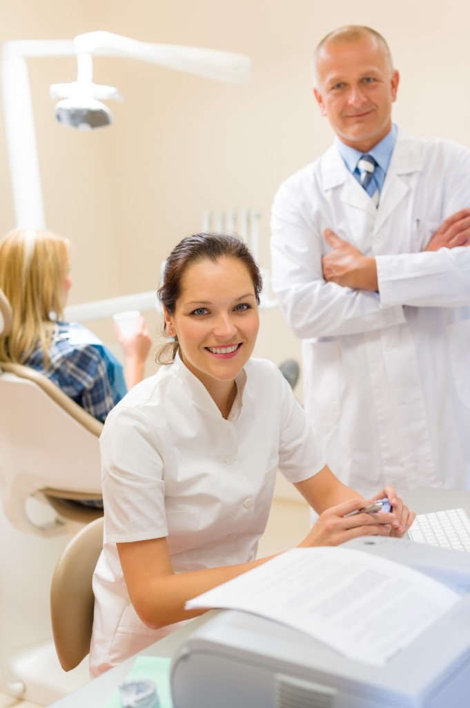 Dentist with assistant smiling at dental surgery