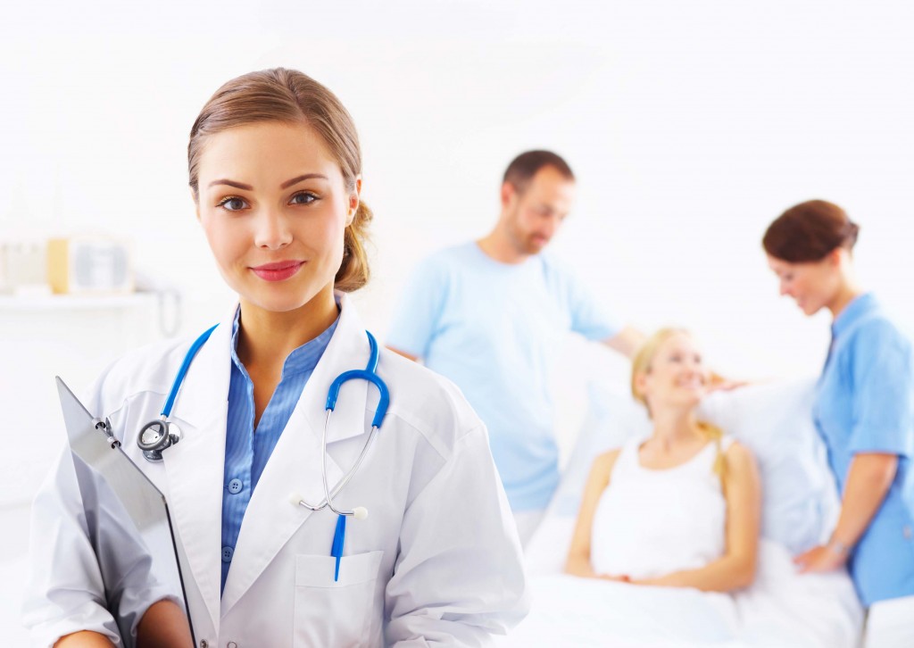 Portrait of a doctor with two of her co-workers talking with a patient in the background